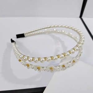 Elegant double-layered headband with white pearls and floral accents on a white stand