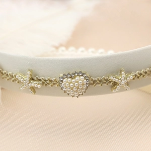 Detailed close-up of a French pearl headband with starfish and heart rhinestone charms