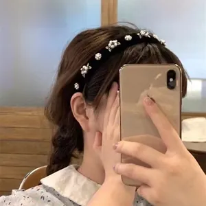 Détail du serre-tête en velours noir élégant avec perles blanches et fleurs en métal