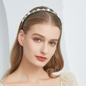 Close-up of pearl and gold star embellishments on an elegant black fabric headband