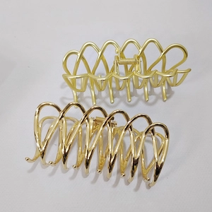 Detail view of large golden metal hair claws with matte and polished finishes