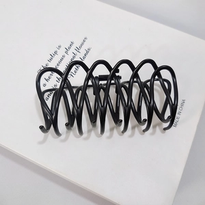 Detailed view of matte black hair claw clip with interlocking spiral teeth and metal spring