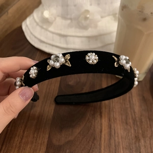 Détail du serre-tête en velours avec perles et fleurs en bronze sur fond de dentelle