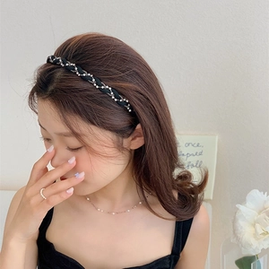 Detail of a braided black velvet headband with sparkling rhinestones and chains for women