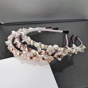 Detail view of flower headbands with faux pearls and rhinestones on a dark textured surface
