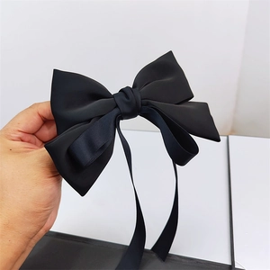 Macro detail of the elegant black satin ribbon bow clip with long flowing streamers
