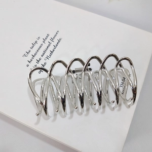 Polished silver metal hair claw clip with wave design on elegant white card