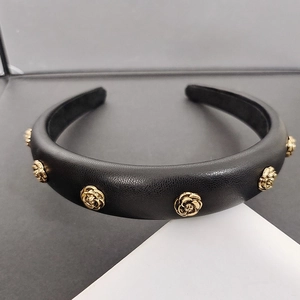 Elegant black lychee leather headband featuring golden camellia floral metal accents
