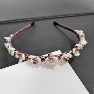 Close-up of purple fabric headband featuring white pearls and brown-purple faceted crystals