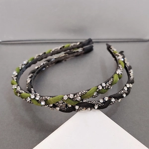 Detailed view of black and green braided headbands with sparkling rhinestones on base