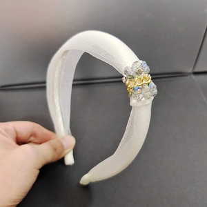 Détail d'un élégant serre-tête en organza blanc avec perles de cristal et décor de chaîne dorée