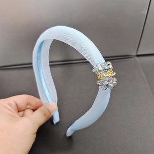 Détail d'un serre-tête en organza bleu clair avec perles de cristal et chaîne dorée