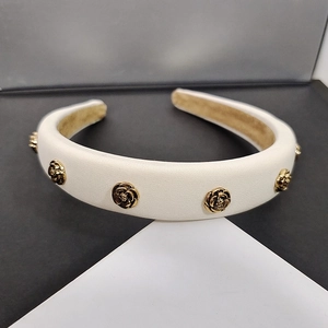 Detailed macro view of white padded camellia headband with vintage gold rose ornaments