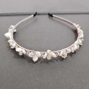 Detailed view of floral headband with white shell petals and sparkling rhinestones