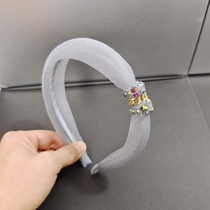 Détail d'un serre-tête en organza gris clair avec perles mauves et chaînes dorées