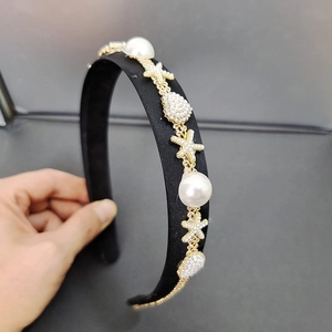 Detailed side view of black satin headband with large pearls and gold starfish elements