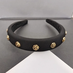 Close-up of padded black satin headband with vintage golden 3D metal roses