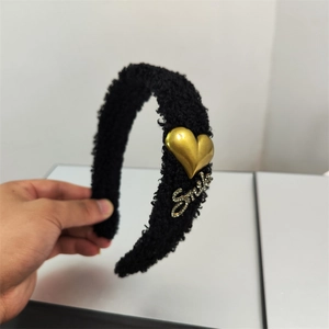 Detail of black faux lamb wool headband featuring golden heart and Smile lettering charm