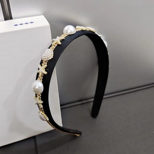 Detail of elegant black fabric headband featuring large pearls and gold starfish motifs