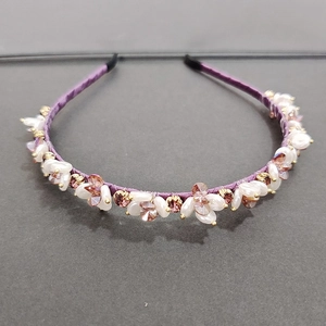 Detailed close-up of purple satin headband with white faux pearls and brown crystals