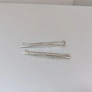Detail view of two silver barrette clips with sparkling round rhinestones on grey surface