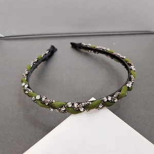 Detail of dark green woven headband with rhinestone chain and twisted fabric texture
