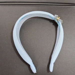 Détail macro du serre-tête en organza bleu clair avec perles cristal et embouts doux
