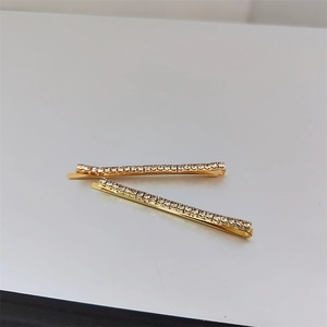 Detailed view of two minimalist gold-plated hair pins with sparkling rows of rhinestones