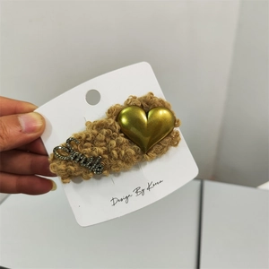 Close-up of caramel plush hair clip with golden heart and rhinestone Smile lettering