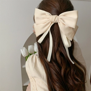 Elegant cream satin bow hair clip with long ribbons for women seen from back view