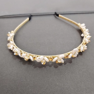Close-up of thin gold headband featuring white pearls and champagne crystal rhinestones