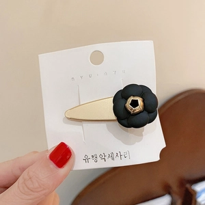 Eleganter schwarzer Kamelien-Haarclip mit goldenem Zentrum auf Premium-Displaykarte