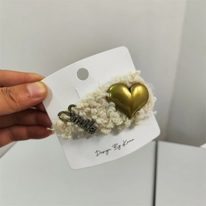 Detail of plush cream faux fur headband with a gold heart and Smile crystal lettering