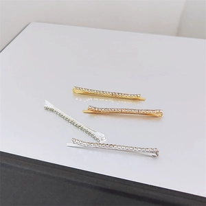 Close-up of four minimalist rhinestone hair clips in gold and silver metal finishes