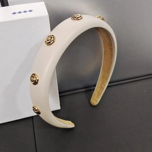 Detail of beige padded headband featuring golden metal rose ornaments and soft faux leather texture