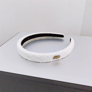 Close-up of white tweed headband with vintage gold buckle and soft fabric texture