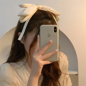 Detail of elegant cream satin bow hair clip with ribbons on woman hair