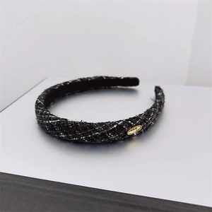 Detailed view of black tweed headband with silver metallic threads and gold buckle