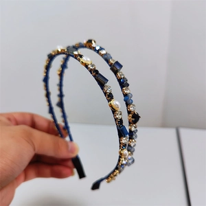 Detailed view of handmade headband with blue crystals and pearls on satin base