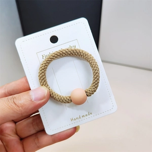 Détail d'un élastique à cheveux haute résistance avec perle mate sur sa carte