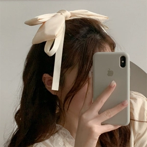 Detail shot of a cream-colored satin bow hair clip styled on the back of the head