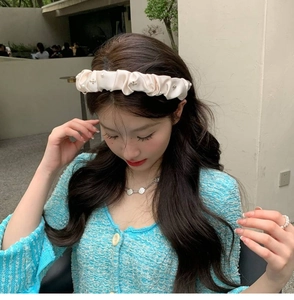 Detail of cream satin pleated scrunchie headband with pearls and metal cross decor