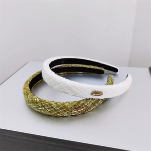 Detail view of tweed headbands in cream and green with decorative gold metal buckles