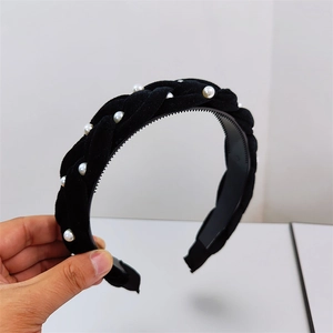 Close-up of black velvet braided headband with white pearl accents and non-slip inner teeth