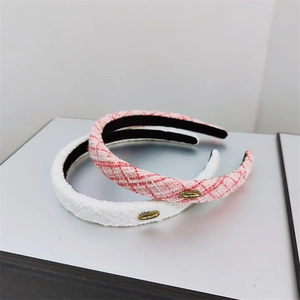 Detail of tweed hairbands in white and red-white checkered fabric with gold plaques