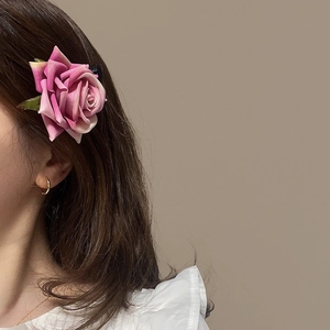 Elegante fermaglio per capelli con rosa sfumata rosa e foglie verdi sui capelli