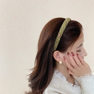 Detail showing the grass green woven headband texture with a side gold metal logo plate