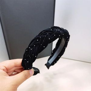 Detalle de una diadema trenzada de terciopelo negro con elegantes lunares blancos