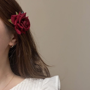 Dettaglio del fermaglio per capelli a rosa rosso scuro su capelli castani con luce soffusa
