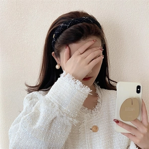 Close-up of black tweed headband with gold buckle detail and elegant pearl styling